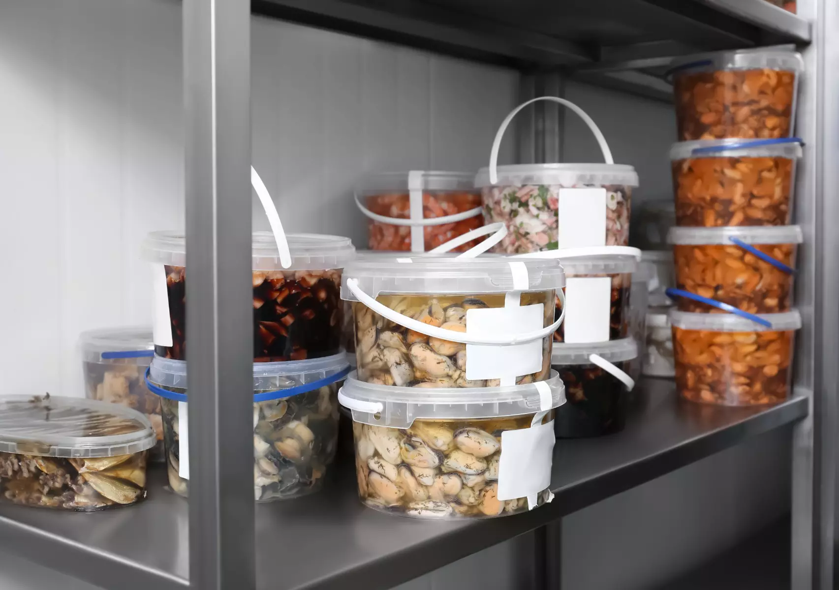Plastic food storage containers on a shelf in a fridge with seafood