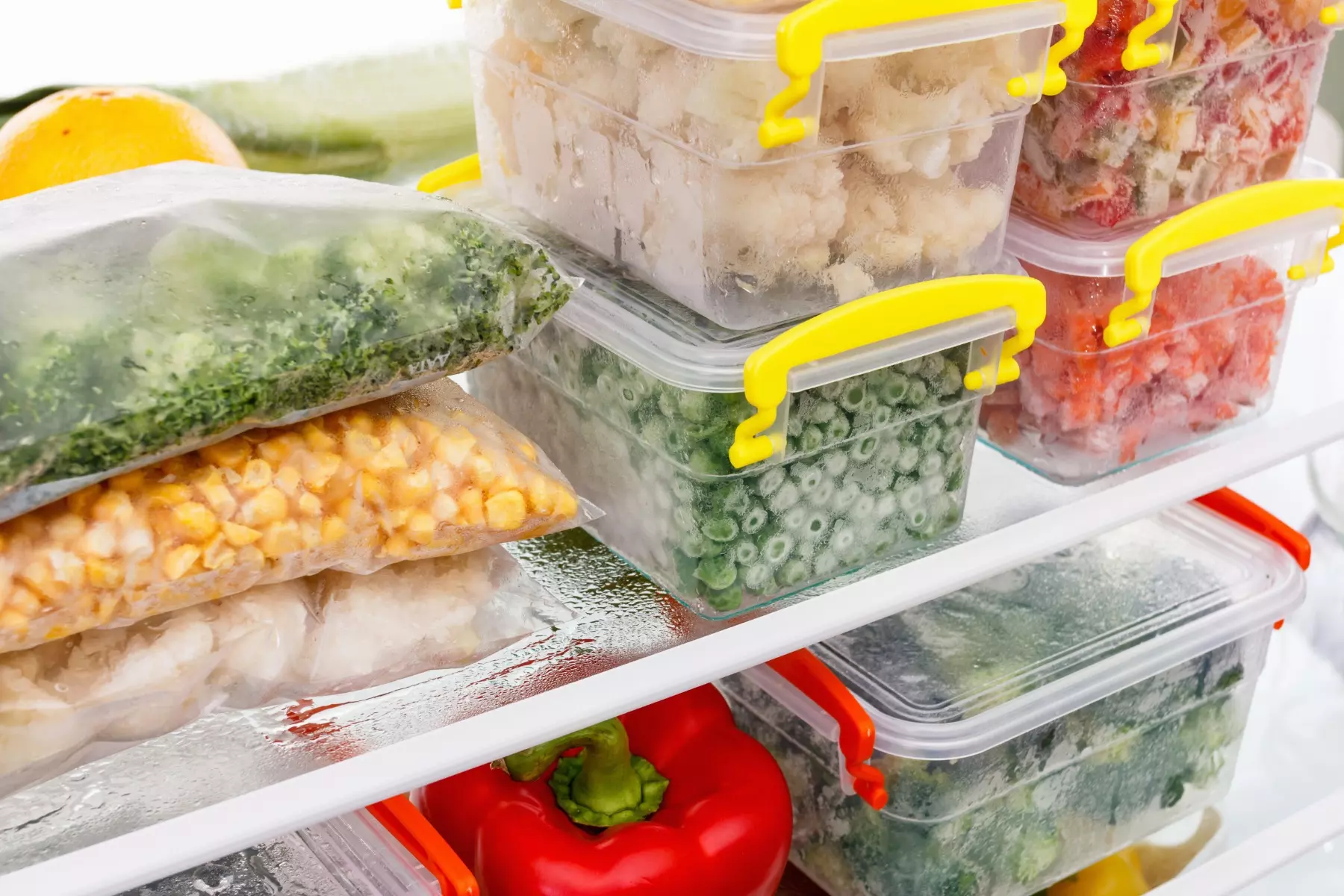 Frozen and cold vegetables in a fridge stored in plastic containers.