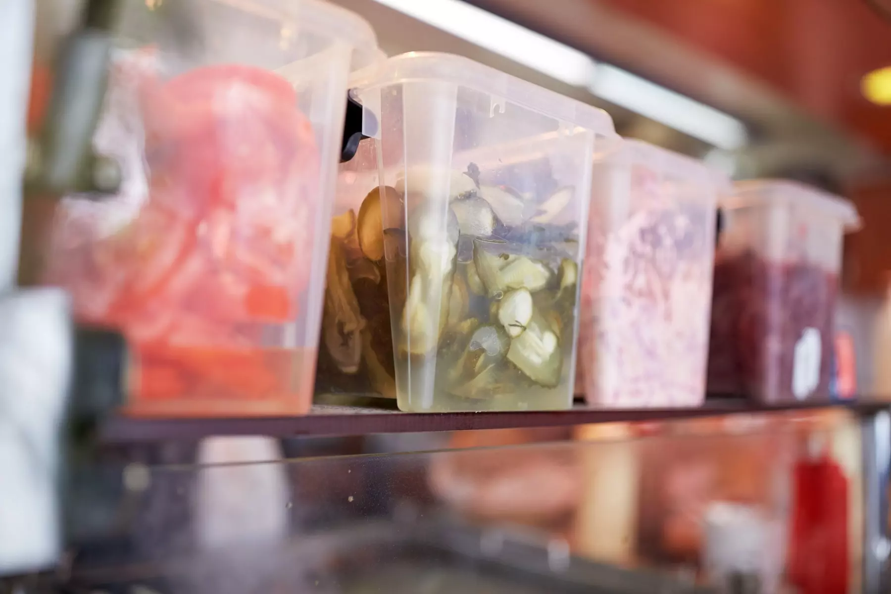 Sliced ingredients placed in plastic food storage containers.